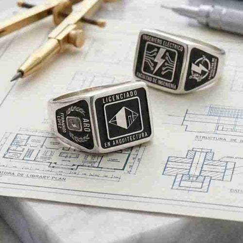 Anillos de graduación personalizados en plata para Arquitecto e Ingeniero Eléctrico sobre planos