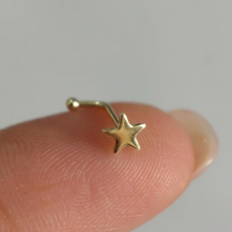 Piercing estrella de oro 10K Pier210k sobre la yema de un dedo