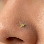 Piercing de estrella dorada colocado en la nariz