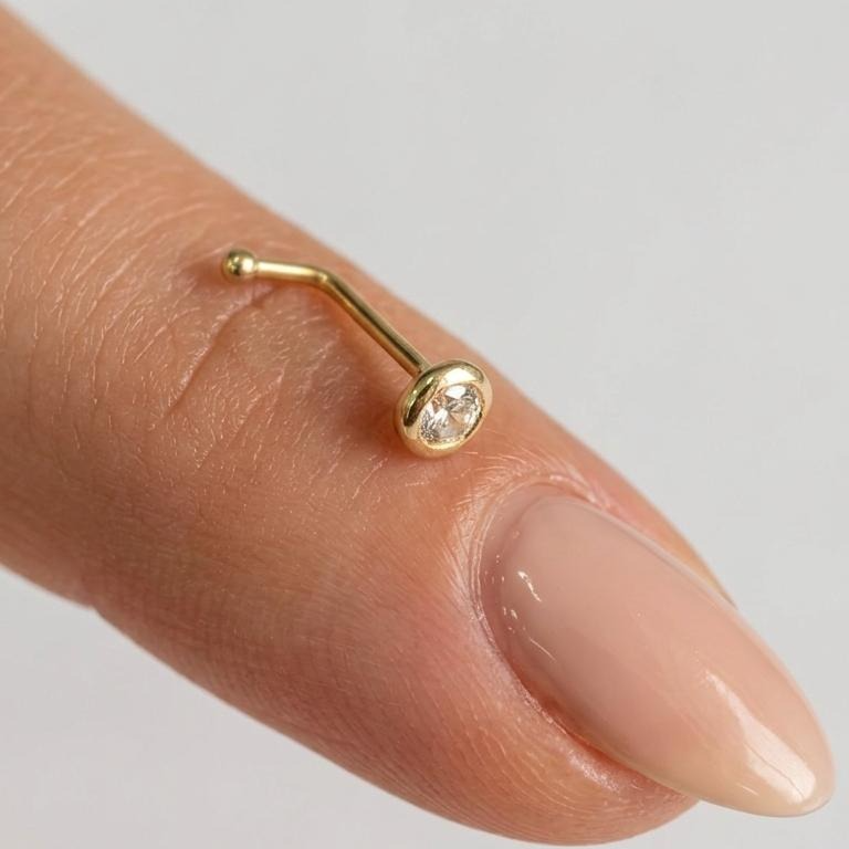 Piercing curvo Pier610k con borde dorado liso sobre un dedo