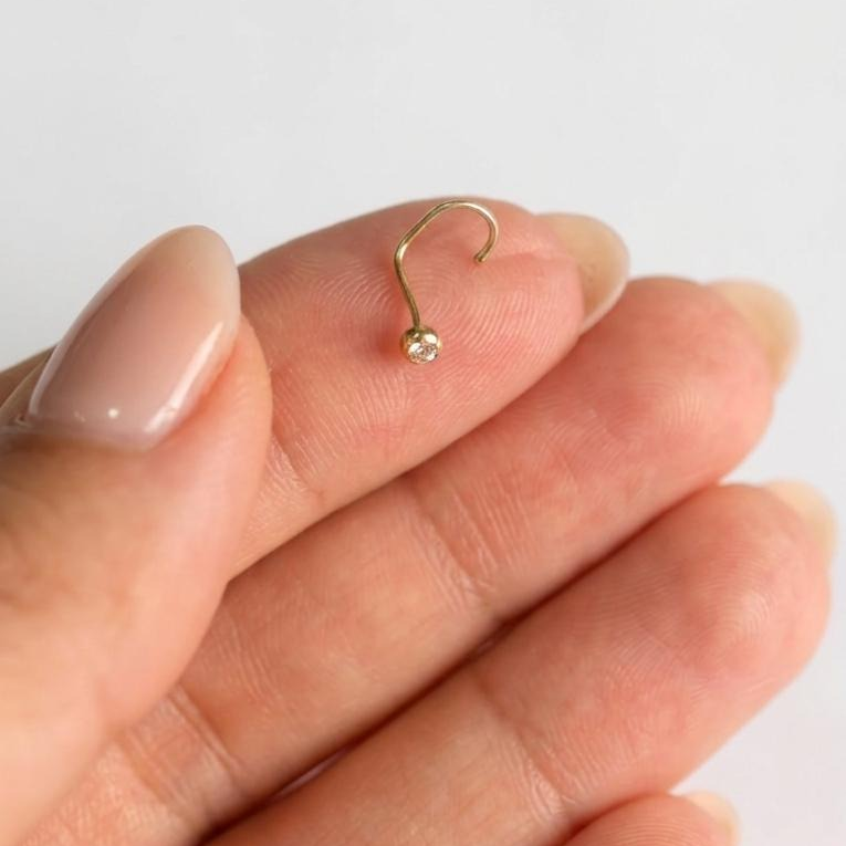 Piercing nasal de oro 10K con curva especial sobre los dedos